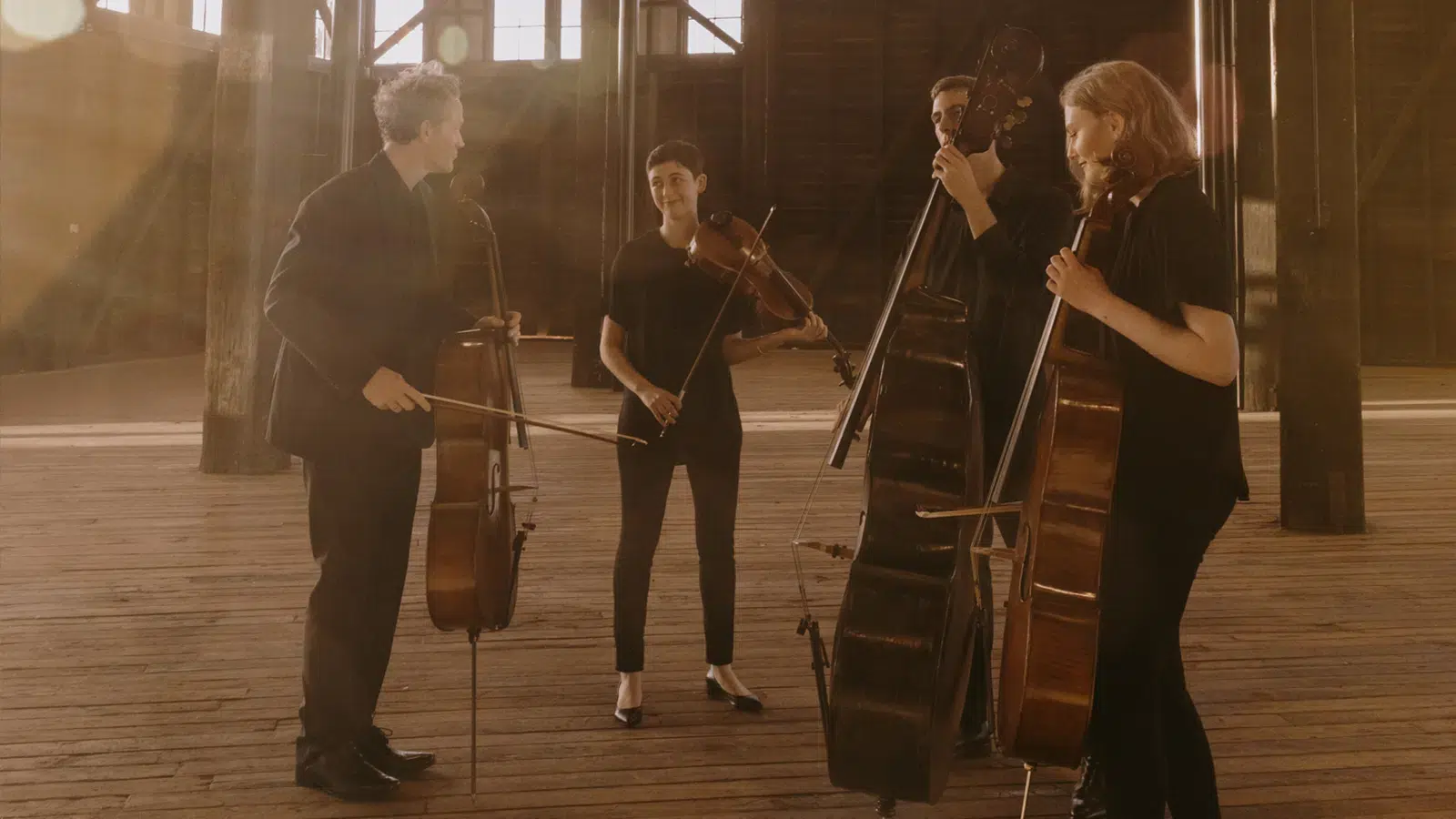 Four classical musicians stand in a hall holding their instruments at an autism friendly concert