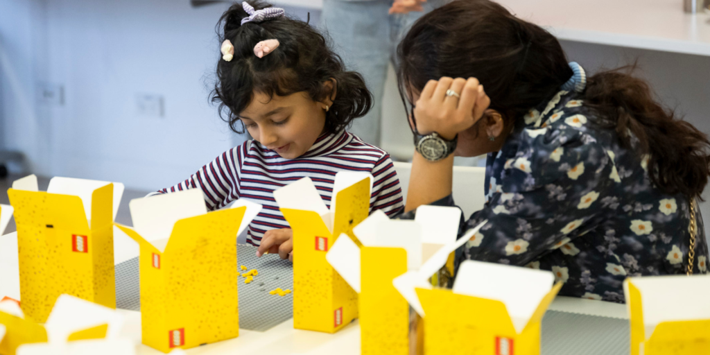 A young girl plays with lego with her parent/carer