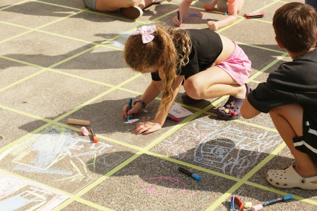 Young girl drawing with chalk on the ground